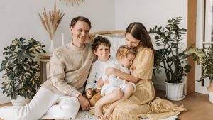 Happy family of four enjoying quality time together in a cozy, plant-filled room.